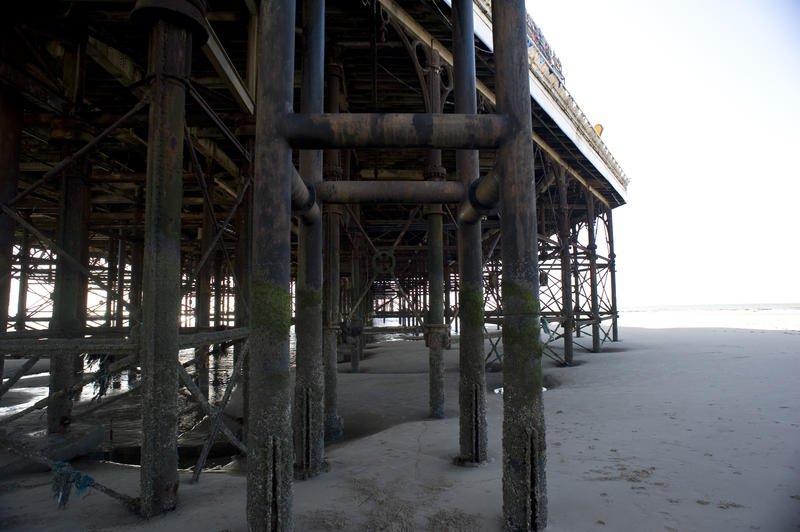 View underneath Blackpool pier looking through the supports and sand towards the ocean at low tide