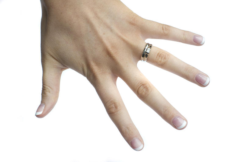 a young ladies hand with both wedding and engagement rings