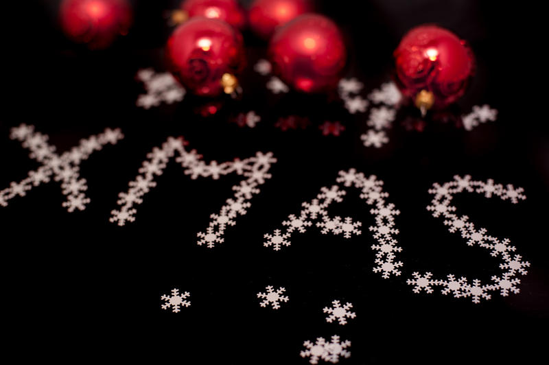 Decorative Xmas greeting with tiny little white snaowflakes and red Christmas baubles on a black background