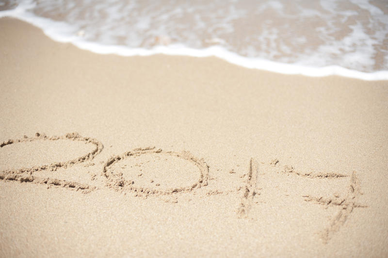 2017 seaside New Year greeting with the date hand drawn on the golden beach sand alongside the edge of the surf