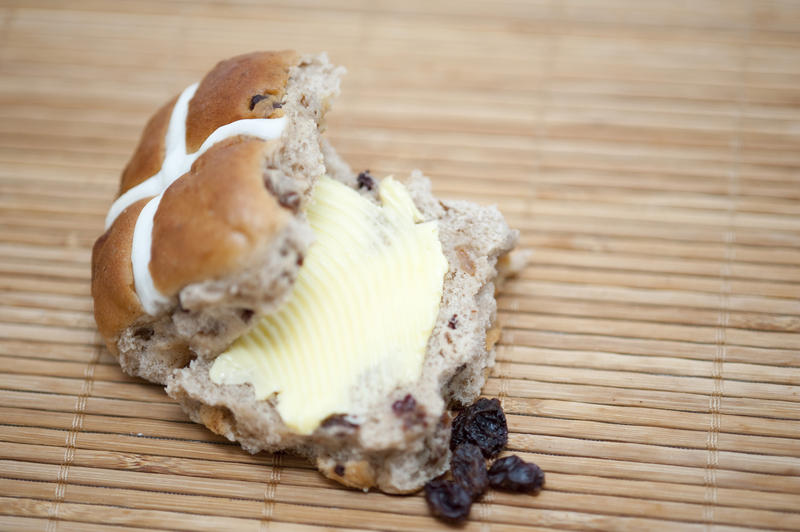 Delicious buttered fresh spicy Easter Hot Cross Bun with raisins