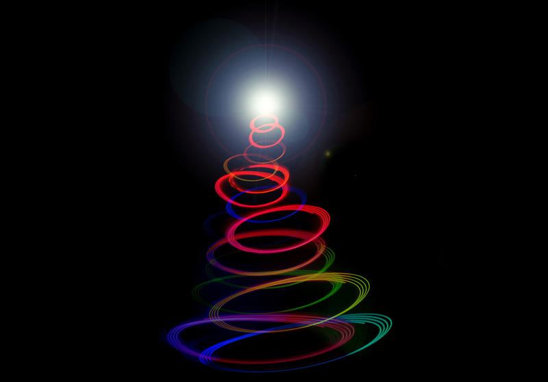 Abstract twirled Christmas tree light in multiple vivid colours of the rainbow coiled in a conical shape to a glowing tip