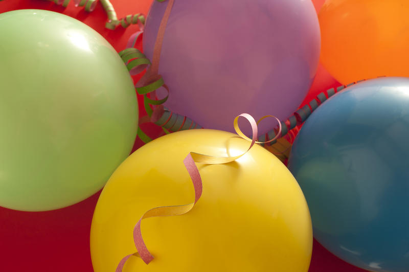 Party or celebration background of colorful balloons and spiral streamers in a close up full frame view from above
