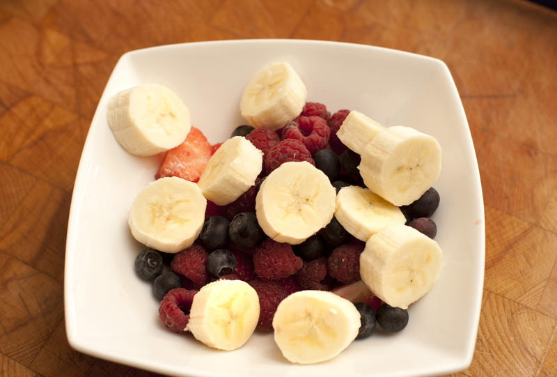 Serving of fresh sliced banana and assorted berries with raspberries, strawberries and blueberries for a healthy breakfast or dessert rich in vitamins