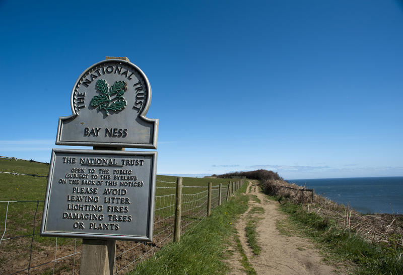 National Trust signboard for Bay Ness on the Cleveland Way path crossing the headlands and cliffs of the North Yorkshire coast