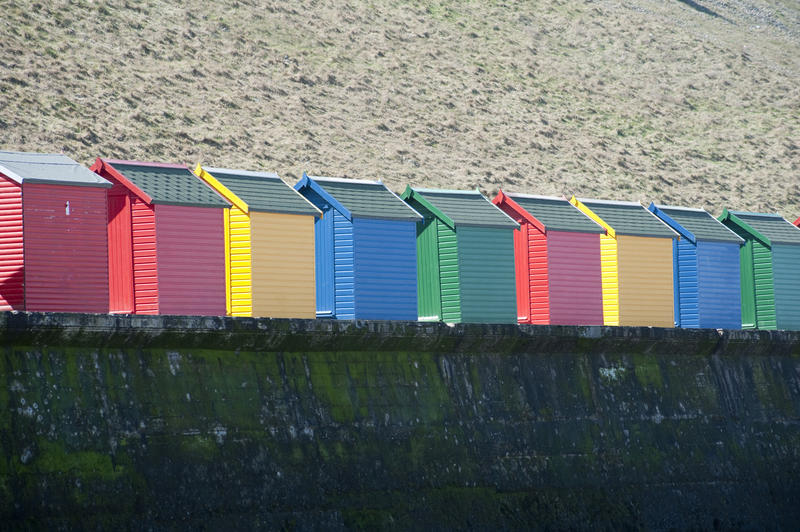 Row of colourful wooden beach huts on Whitby West Cliff