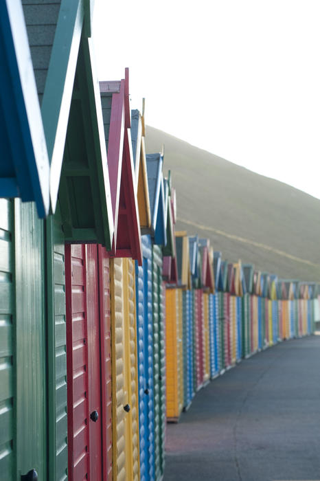 Receding line of colourful wooden beach huts on Whitby West Cliff in Yorkshire
