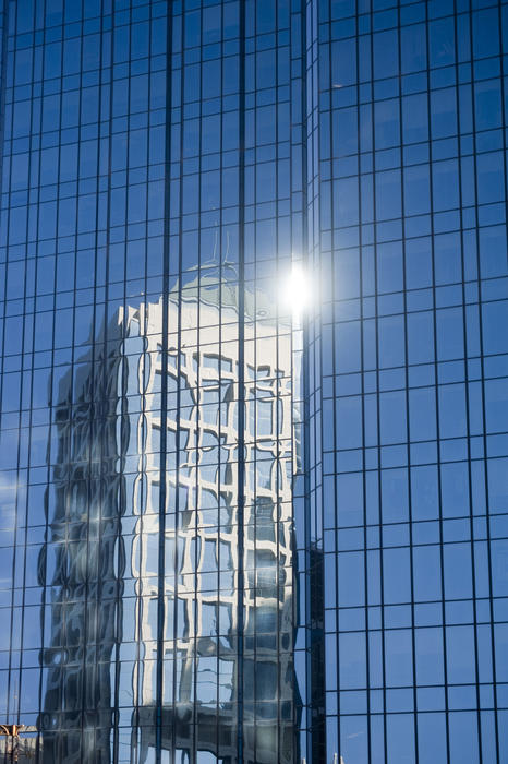 Reflection of Architectural Building from Other Glass Walled Building with Glowing Light on Top