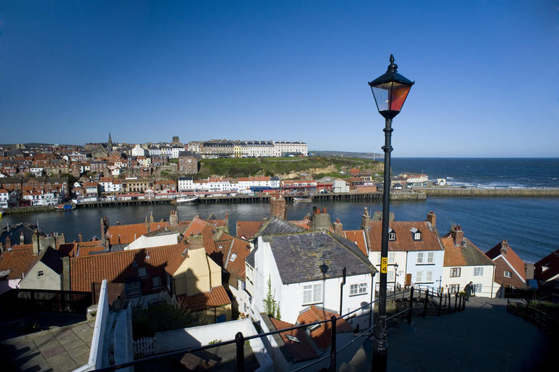 View from the 199 Church Steps of Whitby town and the River Esk with the harbour piers and ocean visible in the distance