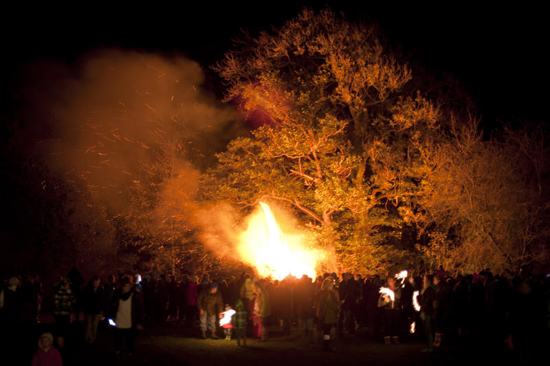 Bonfire party with a crowd of people gathered together around a blazing fire on a field to celebrate Bonfire Night or Guy Fawkes - not model released