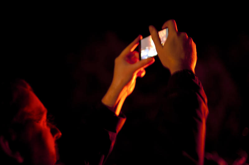 Man taking a photo of a bonfire on Bonfire Night or Guy Fawkes with the image visible on the viewfinder screen - not model released