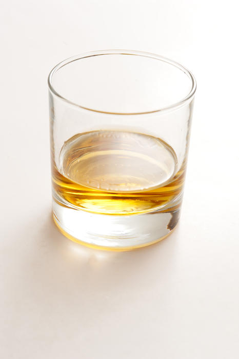 Glass of bourbon whiskey distilled from fermented corn mash in America with an alcohol content of 40 percent or more by volume, on a white background with copyspace