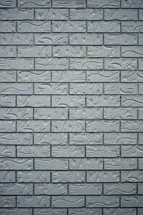 Architectural background texture of a grey brick wall with decorative patterned bricks in vertical format