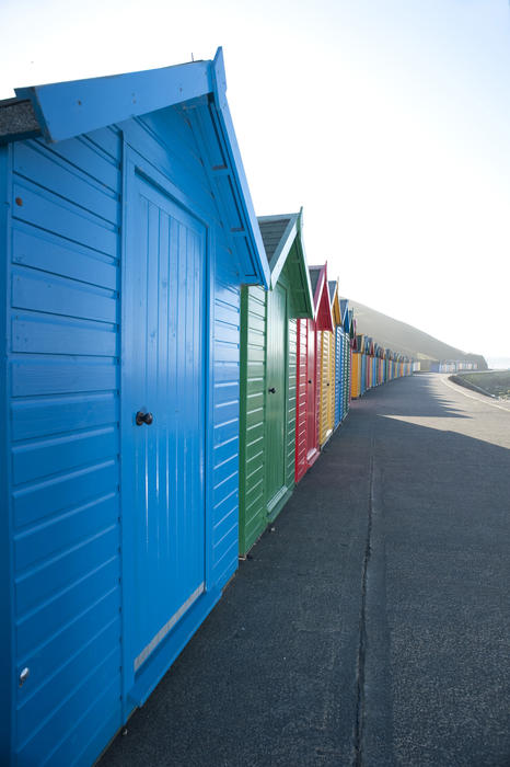 Row of brightly coloured beach huts receding into the distance along the West Cliff in Whitby, Yorkshire