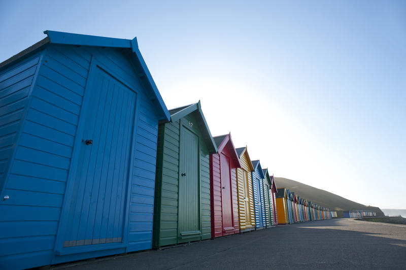 Row of brightly coloured beach huts on the seashore at West Cliff in Whitby in Yorkshire, England