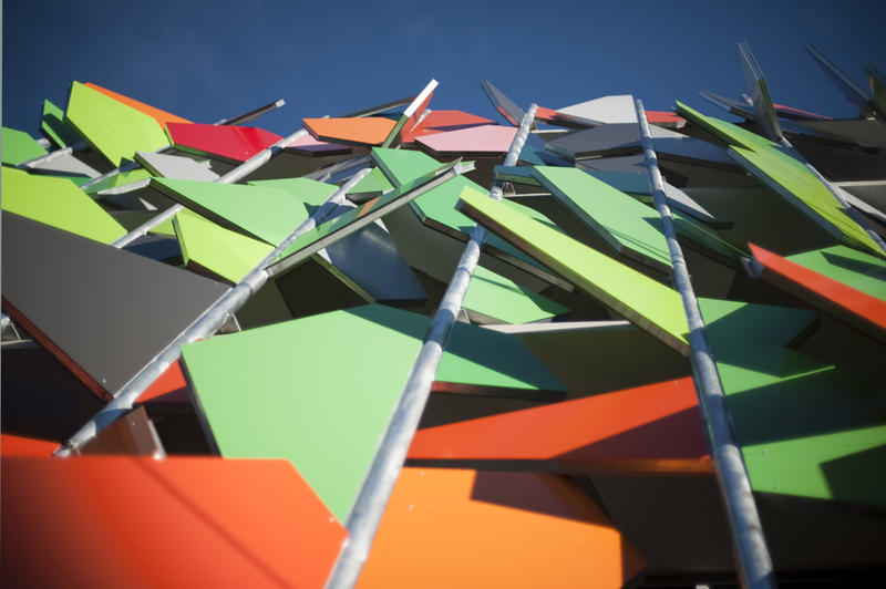 Modern colourful building facade in Melbourne adorned with multicoloured angular panels in random orientation, low angle view
