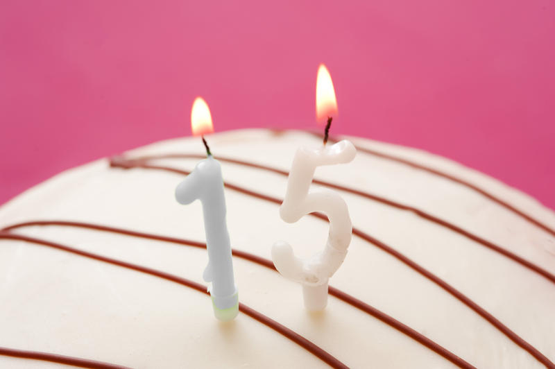 Close up White Candles on a Cake for 15th Birthday Celebration Against Pink Background.