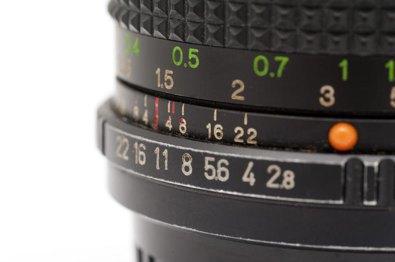 Close up of aperture and distance numbers on a Black Camera Lens on White Background