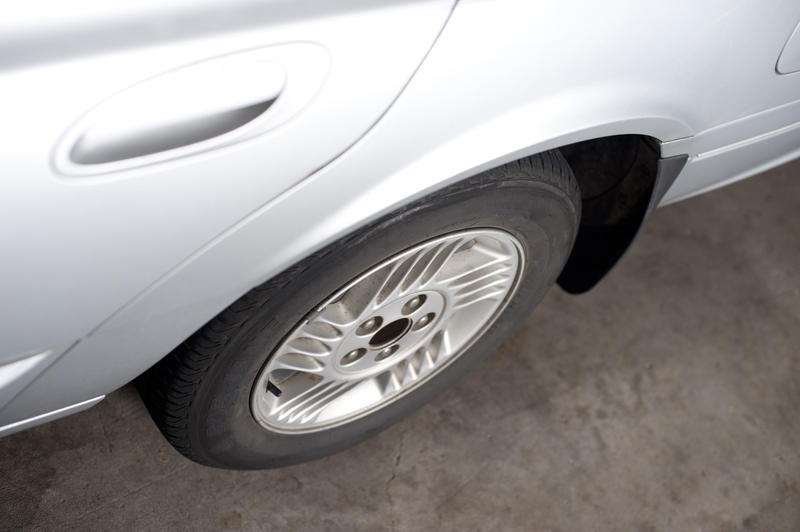High angle view of the wheel and side door of a white car parked on asphalt