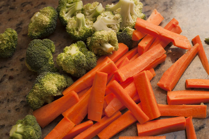Fresh carrots cut into batons with florets of young broccoli ready to be cooked and served for dinner, closeup high angle view