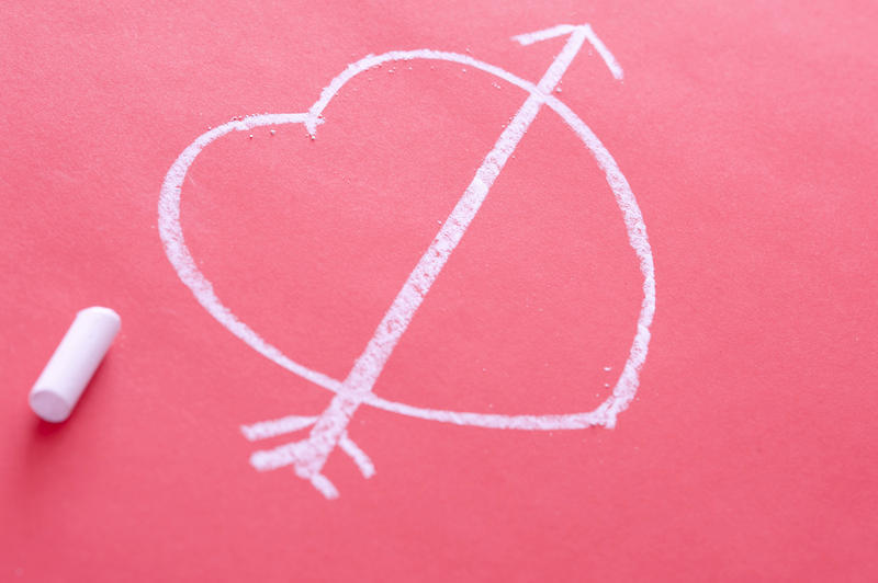 Romantic chalk heart drawing with a Cupids arrow on a red background conceptual of love, Valentines Day or anniversary