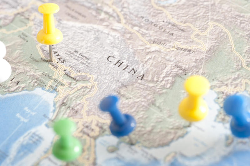 Close Up of Multi-Colored Thumb Tacks as Location Markers Inserted in Map of China
