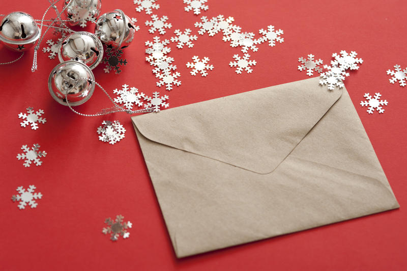 Christmas card or correspondence with a sealed blank envelope lying on a red background with scattered stars and silver bells