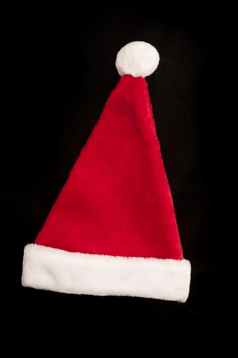 Close up Red and White Santa Claus Hat Isolated on Black Background. Emphasizing Copy Space.