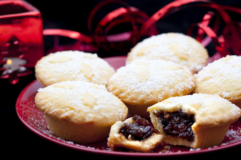 Serving of freshly baked Christmas mince pies on a plate with one opened to display the rich fruity filling for a delicious seasonal treat