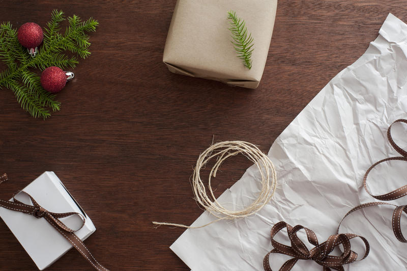 Preparations for Christmas with twine, ribbon, baubles , pine branch and gifts laid out on a table for gift wrapping and decorating, overhead view with copyspace