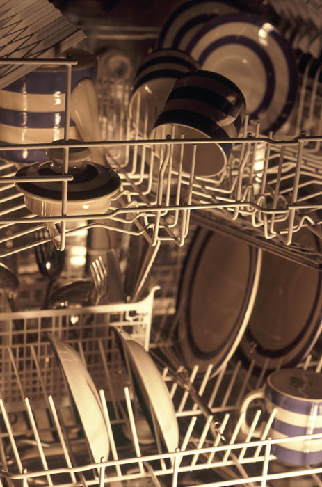 Inside of a dishwasher stacked with clean plates, bowls and mugs at the end of a washing cycle in a health and hygiene concept