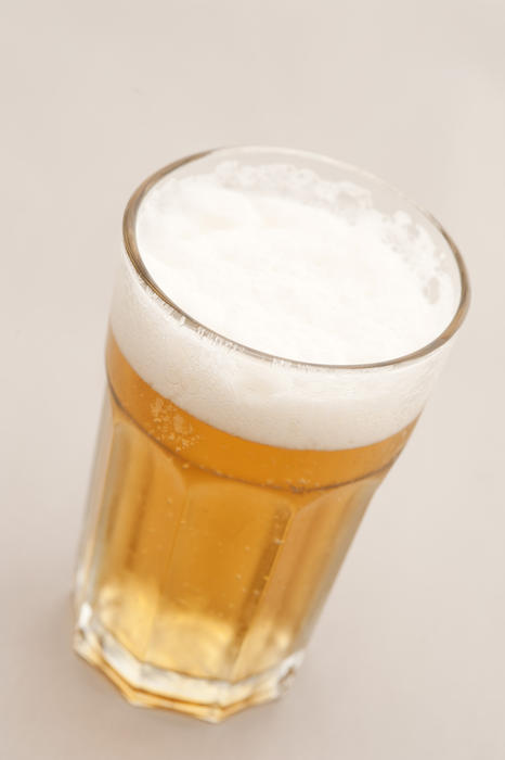 Refreshing cold beer or lager in a glass with a good frothy head on a white background viewed high angle
