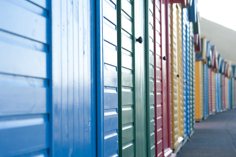 View along a row of brightly coloured wooden beach huts on Whitby West Cliff with shallow dof
