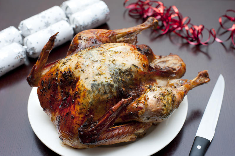 Appetizing crispy brown whole roast Christmas turkey served on a plate ready to be carved for Christmas dinner