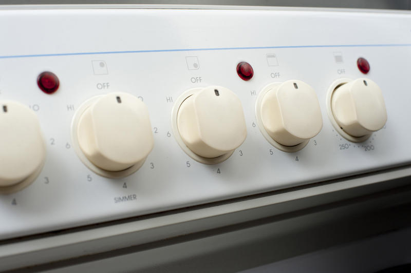 Row of control knobs and thermostats on a kitchen cooker or stove for controlling the power and temperature