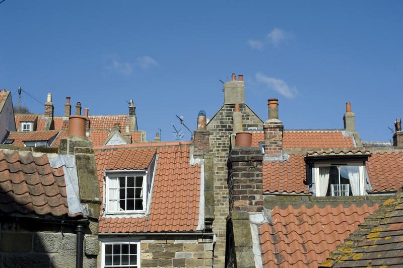 Cottage roofscape in a traditional English village with red roof tiles, clay chimney pots and large cottage pane windows