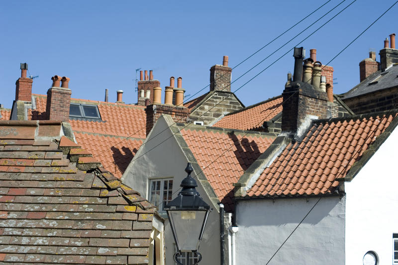 Typical English cottage rooves with their steep pitch and red roof tiles against a blue sky