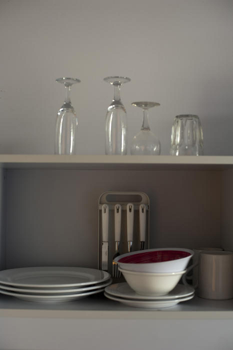 Open kitchen shelves for storage with neatly stacked dinnerware, crockery, glasses and cutlery