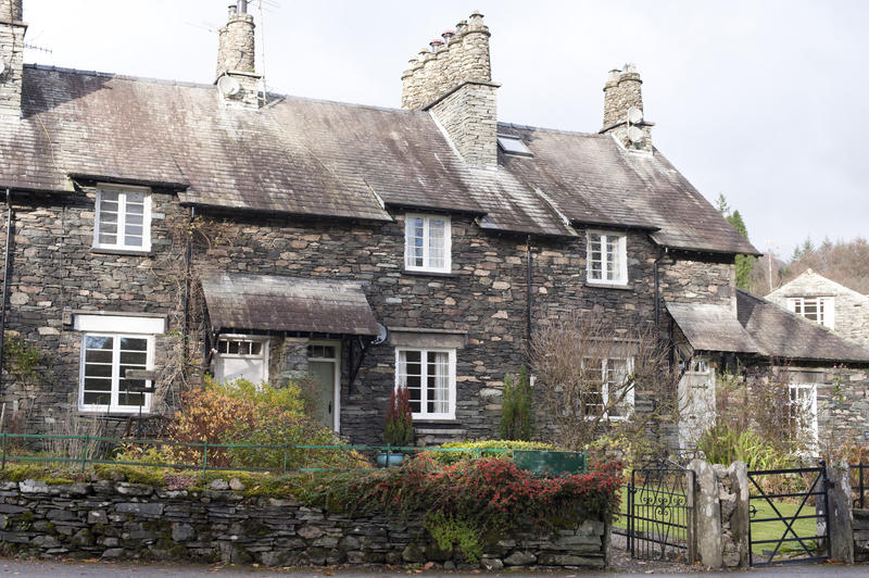 Row of picturesque stone cottage at Skeklwith Bridge in Cumbria with traditional cylindrical stone chimney pots and neat cottage gardens