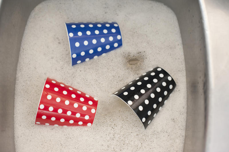 Close up Dish Washing Red, Blue and Black Cups with White Polka Dots Design at the Aluminum Sink