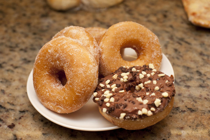 Plate of assorted ring doughnuts with sugared and chocolate glazed donuts ready for a tasty breakfast or teatime