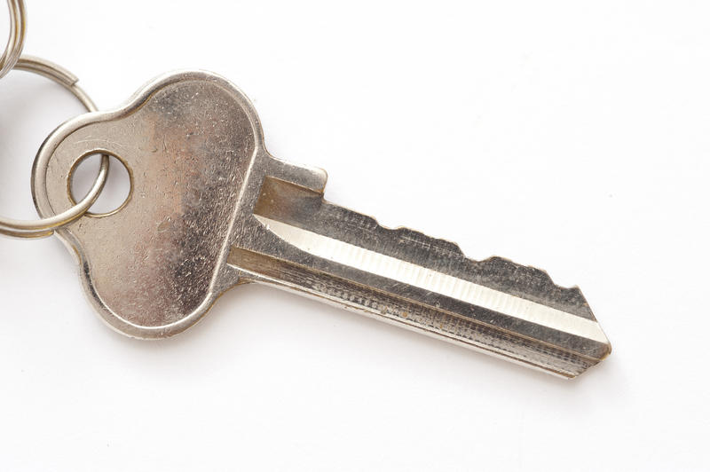 Close up Single Silver Door Key on a Ring Isolated on White Background