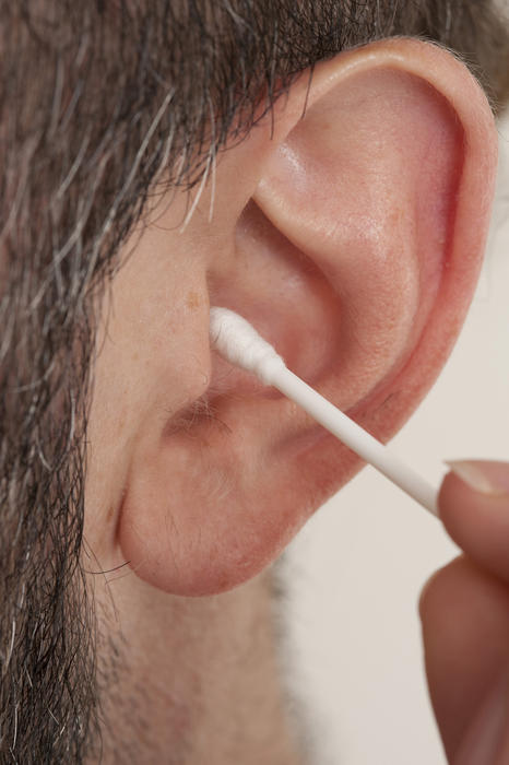 Person de-waxing their ear using a cotton bud in a personal hygiene and healthcare concept, close up view