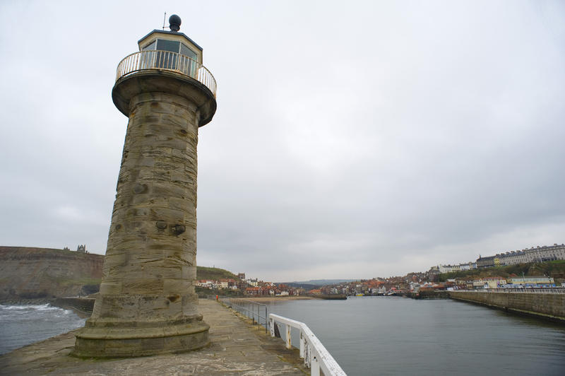 Old stone lighthouse on the end of the pier in Whitby harbour to act as a navigation guide and warning for shipping