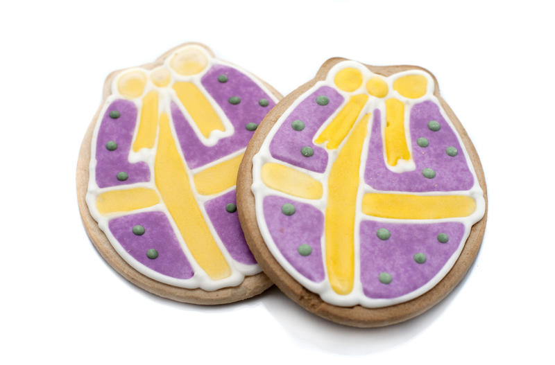 Decorative Easter biscuits in the shape of Easter eggs covered in colourful icing with golden bows