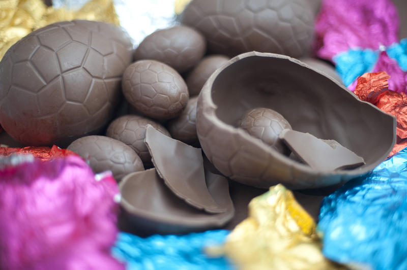 Easter Sunday treat with opened cracked and broken chocolate Easter eggs lying amongst their colourful foil wrappers