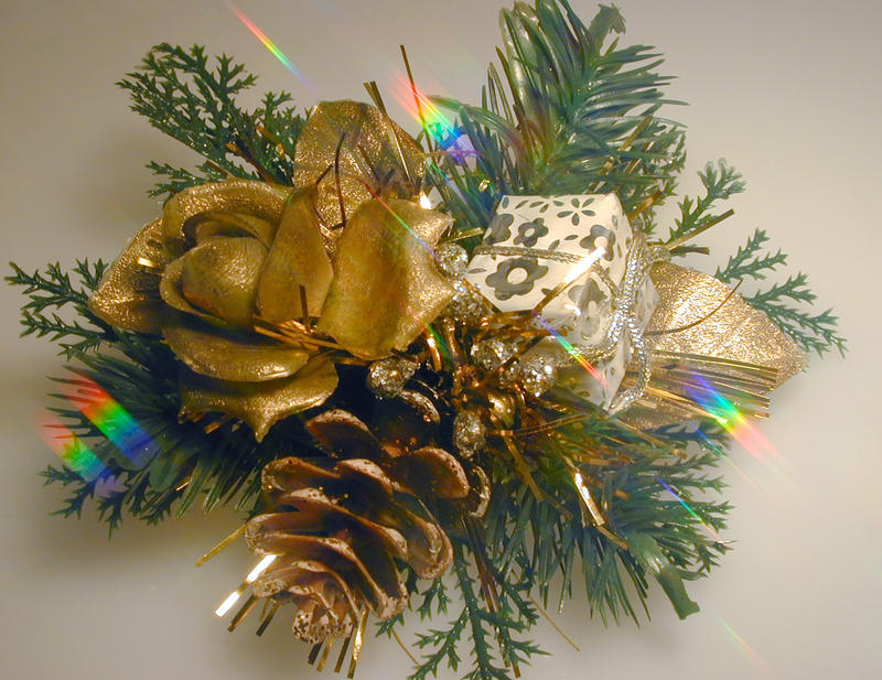 Festive Christmas decorative bundle with a gold flower, gift pine cone and berries in green foliage, close up view with colorful rainbow sparkle