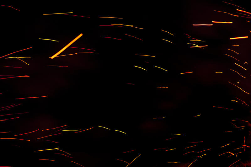 Fire embers flying through the night sky leaving fiery orange trails in a festive background