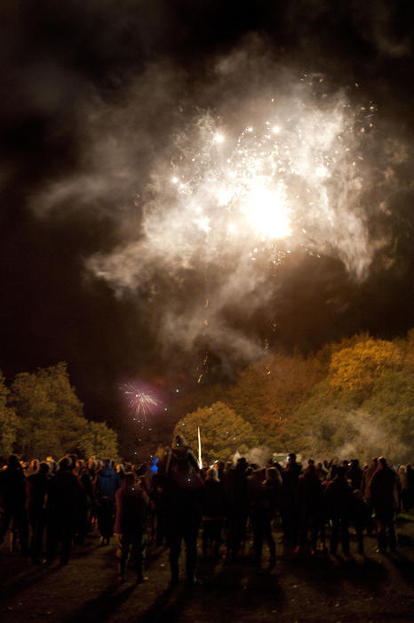 Group of people gathered on a field for a fireworks party with a bonfire and pyrotechnic display on Bonfire Night