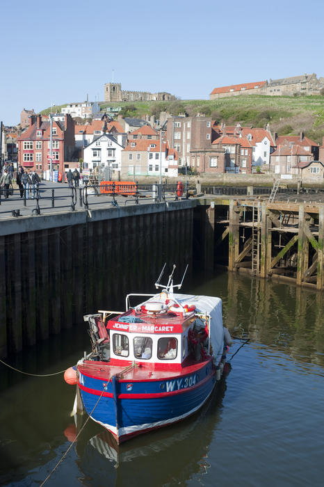Boat moored in the upper harbour at Whitby with the town and St Mary's Church on Tate Hill behind